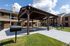 Charming apartment outdoor space featuring a covered picnic area with tables, grills, and a lush green lawn, perfect for relaxation and gatherings.