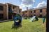 Inviting apartment complex featuring well-maintained brick buildings and a delightful pet play area under a sunny sky.