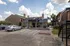 Charming apartment complex exterior with well-maintained landscaping, ample parking, and welcoming clubhouse under a clear blue sky.