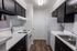 Modern kitchen with sleek dark cabinets, white appliances, and elegant marble countertops, offering a stylish and functional workspace.
