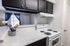 Charming kitchen with modern white appliances, elegant marble countertops, and a cozy view into the living area through a stylish open window.
