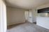 Inviting living room with plush carpeting, bright natural light, and seamless connection to kitchen area, perfect for modern living.