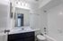 Modern bathroom featuring elegant marble countertop, sleek vanity, and pristine white tile bathtub offering luxury and comfort.