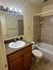 Modern bathroom featuring elegant granite countertop, polished wooden cabinetry, and stylish tiled shower.