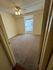 Bright and inviting bedroom with plush carpet, ceiling fan, and large window featuring vertical blinds.
