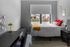 Inviting bedroom with a modern desk, vibrant yellow accents, and urban view through a large window.