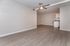 Modern open-plan living area with sleek wood floors and a stylish ceiling fan, leading to a contemporary kitchen.