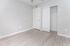 Bright and airy bedroom with sleek laminate flooring and a spacious closet featuring sliding doors.