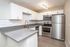 Modern kitchen with sleek stainless steel appliances, elegant white cabinetry, and stylish gray countertops.