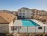 Inviting apartment complex with a crystal-clear swimming pool and scenic mountain views, perfect for relaxing and enjoying the sunshine.