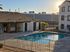 Charming apartment complex with a refreshing outdoor pool, surrounded by serene landscaping and contemporary architecture, basking in warm sunlight.