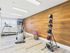 Modern apartment gym featuring state-of-the-art treadmill, elliptical machine, and vibrant medicine balls against a sleek wood-paneled wall.