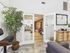 Inviting indoor gym entry with stylish decor, lush leafy plant, and glass doors opening to a state-of-the-art cardio area, perfectly blending comfort and fitness.