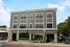 Modern three-story apartment with retail space, featuring stylish gray exterior and large windows, perfect for urban living