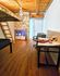 Cozy room with a rustic wooden ceiling, stone wall accents, and a lofted sleeping area, perfect for creative living.