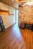 Charming room with rustic stone accent wall, stylish wooden ceiling, and sleek laminate flooring, offering a cozy and inviting atmosphere.