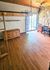 Charming room with wood floors, rustic stone wall, wooden loft bed, cozy workspace, and sliding glass door to balcony.