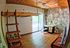 Charming room with rustic wooden loft ladder, stone accent wall, and natural light from sliding glass door opening to a balcony.