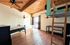 Spacious bedroom with loft bed, rustic wooden ceiling, and sliding glass door opening to natural light.