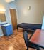 Cozy bedroom with wood flooring, a single bed, built-in sink, and a study desk, perfect for comfort and practicality.