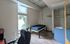 Cozy bedroom featuring a large window, a sleek desk chair, and a minimalist bed with adjacent vanity.