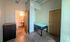 Bright bedroom with cozy bed, minimalist furniture, and en-suite bathroom in a modern apartment.