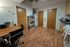 Cozy communal kitchen with a dining area, featuring wood flooring, pantry storage, and welcoming decor.