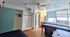 Cozy studio apartment with hardwood flooring, open closet space, large window with blinds, and a well-lit vanity area.