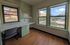 Bright room with large windows offering scenic city views, featuring a built-in desk, shelves, and elegant hardwood floors.