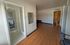 Modern apartment with sleek wooden flooring, an open doorway leading to a bright room, and contemporary fixtures.