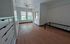 Bright bedroom with hardwood floors, large windows, and ample natural light; features a sleek ceiling fan and built-in storage.