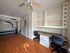 Spacious room with elegant wood flooring, stylish built-in desks, ample storage, and a unique wall design enhancing modern living.