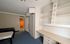 Bright bedroom with blue carpet, built-in shelves, and a desk offering ample storage space.