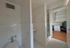 Compact bathroom design with white tiles and view into a cozy workspace featuring built-in shelves and a modern desk chair.
