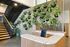 Inviting apartment lobby with a modern staircase, vibrant green wall of plants, and a sleek terrazzo reception desk.