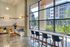 Chic urban cafe interior with stylish seating and large windows showcasing a scenic view of vibrant greenery and modern buildings.