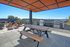 Chic rooftop patio with stylish seating, picnic table, and modern barbecue grills, offering stunning outdoor views.