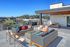 Chic rooftop terrace with plush seating, modern fire pit, and BBQ grills against a scenic backdrop.
