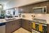 Modern kitchen with sleek cabinetry and integrated appliances, opening to a stylish living area with contemporary decor and vibrant art pieces.