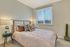 Bright and cozy bedroom with elegant decor, featuring a large window with city views and stylish bedding.