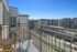 Charming apartment balcony with wicker chairs overlooking a vibrant urban landscape and modern apartment buildings.