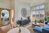 Chic and modern living room with large sunlit windows, stylish decor, and elegant seating area, perfect for relaxation.