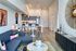 Chic open-plan living room with modern decor, sleek kitchen, and cozy dining area, featuring stylish furniture and warm lighting.