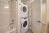 Modern bathroom featuring a sleek white bathtub and a convenient in-unit washer and dryer set.