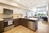 Modern kitchen with stainless steel appliances and an inviting, open-concept living area featuring large windows and stylish decor.