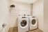 Modern laundry room with sleek washer and dryer set, complemented by a stylish potted plant on a spacious shelving unit.