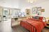 Bright, modern bedroom with a cozy red bed, stylish decor, and a sunlit balcony ideal for relaxation.