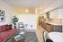Modern open-concept living room featuring a chic red sofa, vibrant decor, and a sleek kitchen with stainless steel appliances and ample cabinetry.