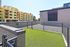 Bright outdoor space with fresh artificial grass, surrounded by a secure fence, offering a serene spot for relaxation amidst modern architecture.