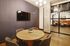 Modern meeting room with a sleek wooden table, comfortable chairs, wall-mounted TV, and a stylish glass partition.